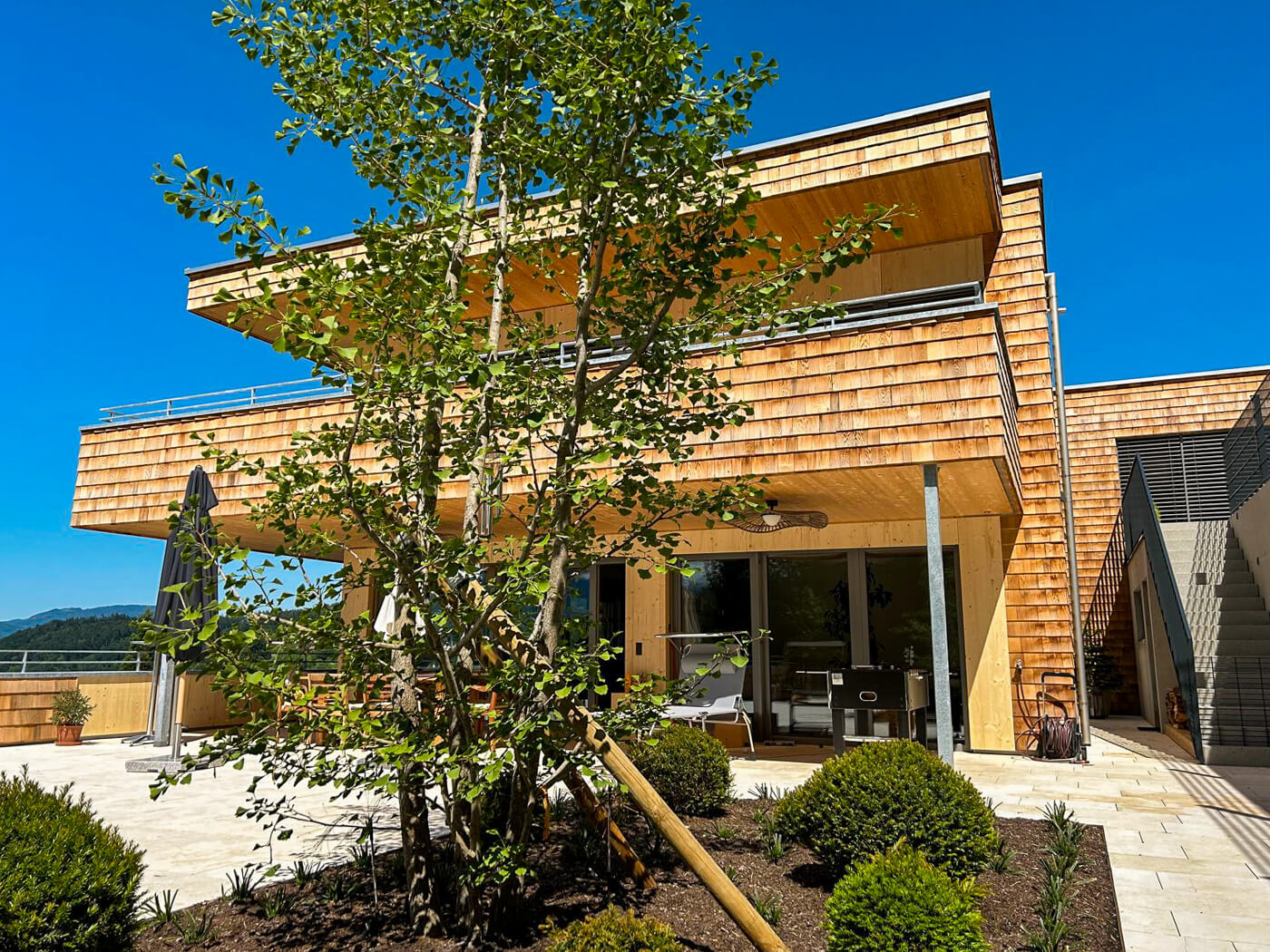 Hausfassade mit Holzschindeln aus Rot Zeder gesgaegt